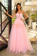 A woman wears a strapless Pink/Yellow ball gown with a sparkling tulle skirt, posing by a glass window.