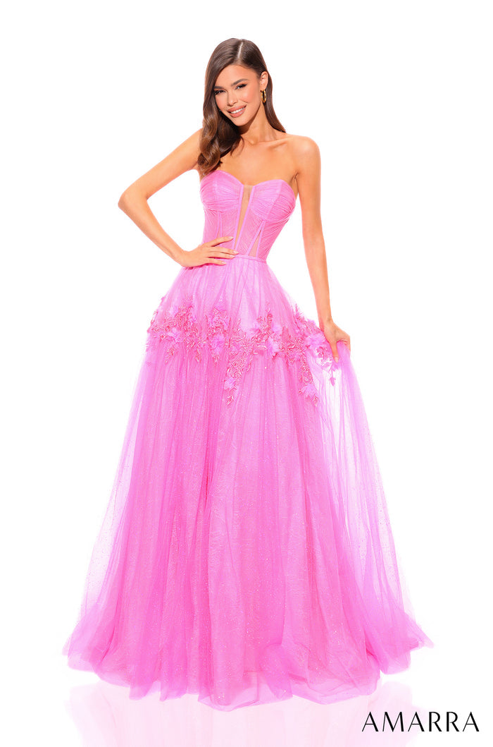 A model wears a strapless neon pink ballgown with a fitted bodice and flowing tulle skirt decorated with lace.