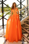 A model wears a floor-length, neon orange ball gown with floral embellishments and cold-shoulder straps.