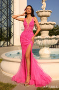 A model wears a bright pink sequined gown with a high slit, posing by a white fountain.