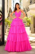 A woman models a hot pink tiered ball gown with spaghetti straps in an elegant indoor setting.