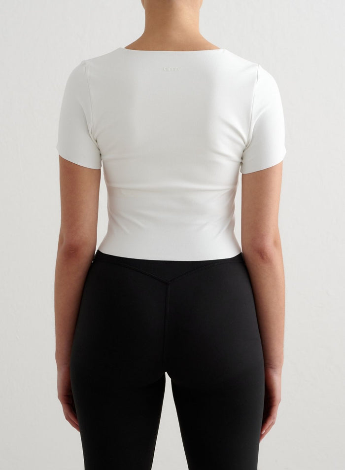 Valkoinen lyhythihainen aim'n Sense Short Sleeve Bralette, jossa on pehmeä second skin -tuntu ja logo selässä.