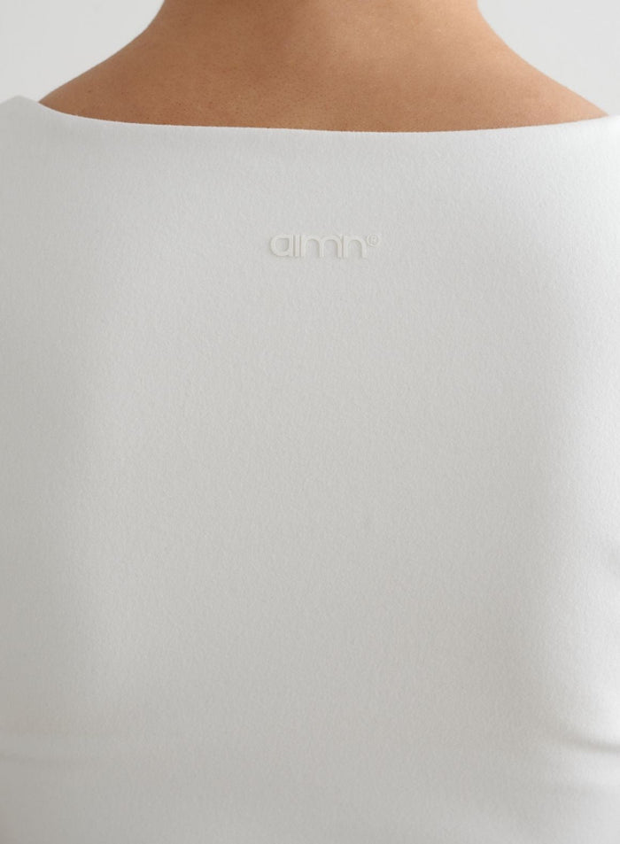 Valkoisen Sense Short Sleeve Bralette -topin takakuva, jossa näkyy kuminen aim'n-logo.